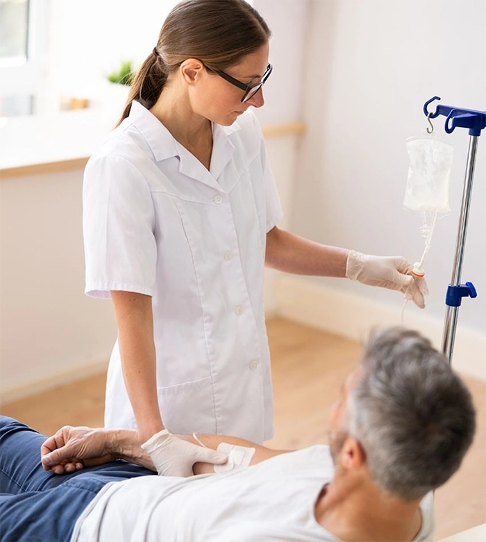 Nurse administers an IV drip to a man in a hospital setting.